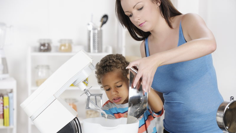 Een moeder gebruikt een keukenrobot met haar zoon.